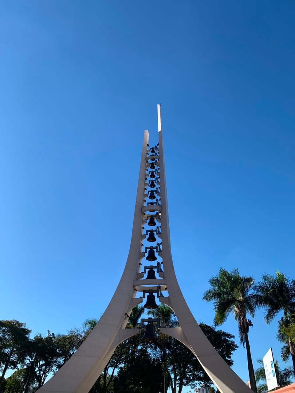 O campanário do Santuário de Aparecida, com os sinos enfileirados na torre branca, contra o céu azul